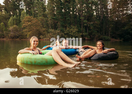 Portrait of happy young adultes sur les chambres à air dans le lac. Les amis passer une journée au bord du lac. Banque D'Images