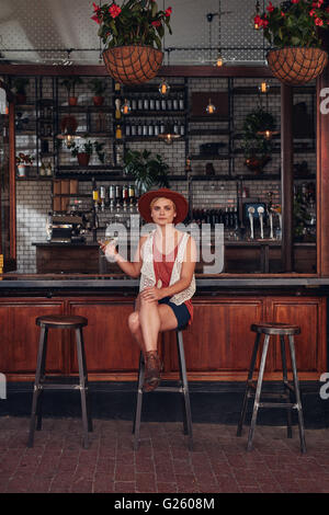 Longueur totale de l'intérieur jeune femme assise dans un café avec un verre. Les femmes de race blanche de détente à un pays Banque D'Images