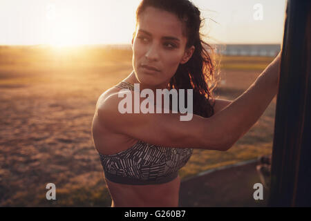 Gros plan de l'ajustement jeune femme en soutien-gorge de sport à l'hôtel. Remise en forme en plein air pensif femme debout sur une journée ensoleillée. Banque D'Images