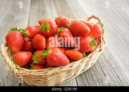 Panier de fraises se dresse sur une table en bois. Banque D'Images