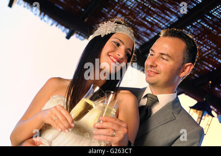 L'époux et épouse toasting with champagne sur une terrasse smiling contact visuel Banque D'Images