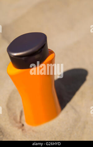 Vue en gros plan sur des bouteilles en plastique de la crème solaire dans le sable Banque D'Images