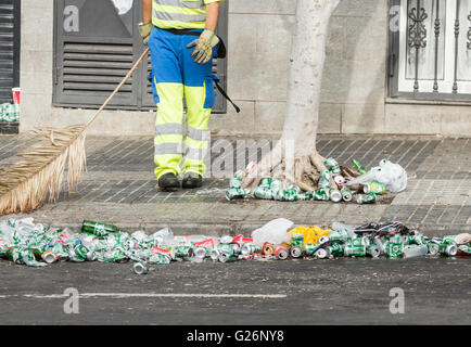 Travailleur du conseil nettoyage des canettes de bière et des gobelets en plastique à l'aide de palm tree branch dans la rue près de stade de football de l'Espagne Banque D'Images