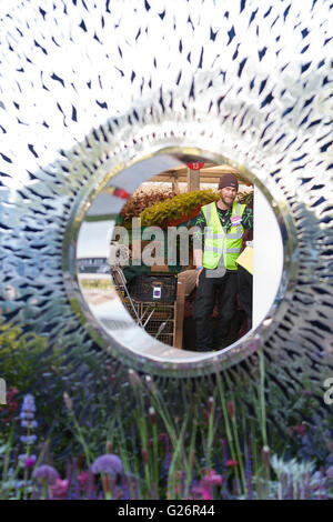 Chelsea Flower Show, London, UK. Travailleur dans une veste fluorescente vue à travers une sculpture réfléchissante sur le David Harber stand. Banque D'Images