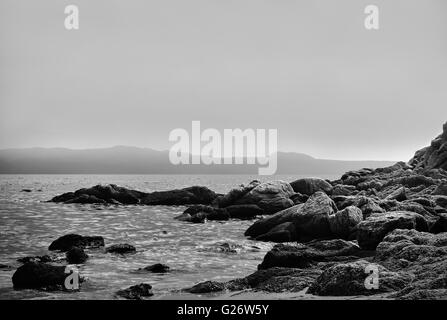 La photo artistique de roches par la mer en noir et blanc Banque D'Images