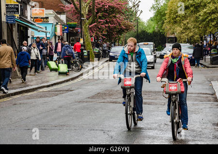 Un couple de cyclistes sur les "Boris Bikes' descente de Queensway à Bayswater, Londres. Banque D'Images