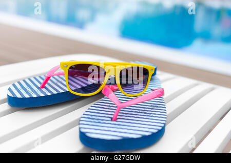 Lunettes de soleil et des ardoises sur une chaise longue au bord de la piscine. Banque D'Images