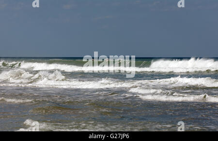 Un groupe de quatre pélicans bruns volant à basse altitude au-dessus le surf sur Apollo Beach, Merritt Island, Florida Banque D'Images