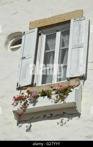 Volets ouverts blanc sur fond blanc bois bois vitrage dans un mur blanc, avec une fenêtre de dialogue de fleurs colorées, Turquie Banque D'Images