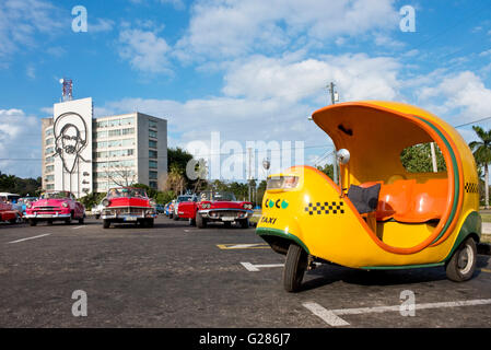 Un coco taxi, taxi de l'Amérique des années 50 et du milieu de l'image de Camilo Cienfuegos sur l'édifice historique de la place de la révolution. Banque D'Images