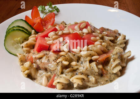 Noix de pin frais pâtes rotini magnifiquement servi avec des légumes et une sauce crémeuse au pesto. Banque D'Images