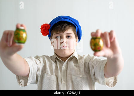 Garçon en cap nationale russe avec girofle holding Easter eggs Banque D'Images