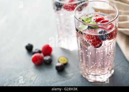 L'eau pétillante avec les framboises et les bleuets Banque D'Images