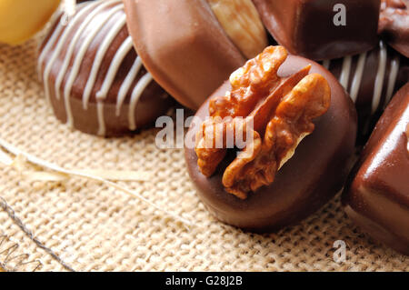 Close up bonbons empilés sur le sac de jute. Chocolat noir et blanc à l'aide d'écrous et de paille décoration. Vue élevée. Com horizontale Banque D'Images