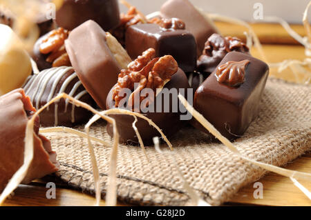 Close up bonbons empilés sur une table en bois. Chocolat noir et blanc à l'aide d'écrous et de paille décoration. Vue de face. L'horizontale Banque D'Images