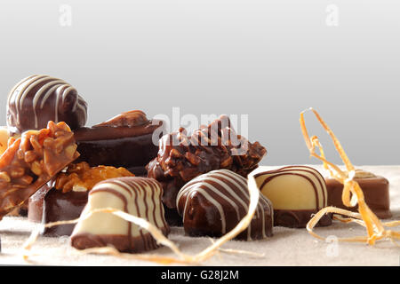 Groupe de bonbons empilés. Chocolat noir et blanc à l'aide d'écrous et de paille décoration sur une table avec nappe marron tissu Banque D'Images