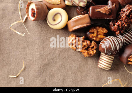 Groupe de bonbons empilés. Chocolat noir et blanc à l'aide d'écrous et de paille décoration sur une table avec nappe marron tissu. Haut Banque D'Images