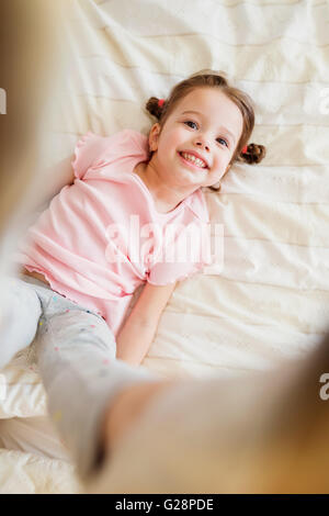 Cute little girl in bedroom sauter sur un lit Banque D'Images