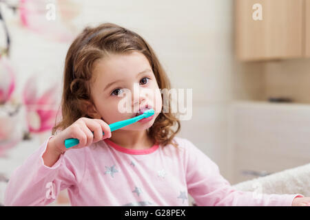 Petite fille en pyjama rose dans la salle de bain se brosser les dents Banque D'Images