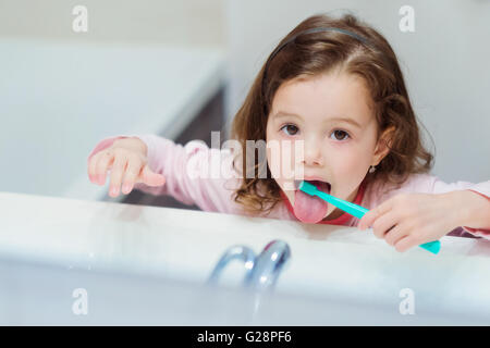 Petite fille en pyjama rose dans la salle de bain se brosser les dents Banque D'Images