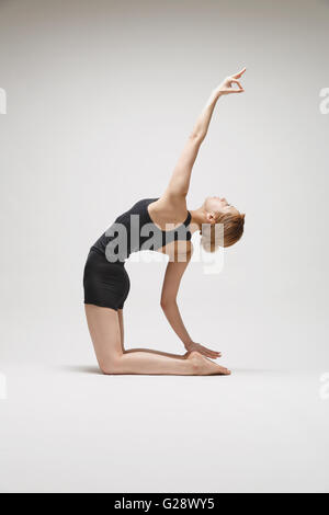 Belle jeune japonaise porter des pantalons noirs et tank top practicing yoga on white background Banque D'Images