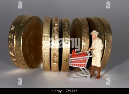 Figurine miniature femme âgée poussant un chariot de supermarché britannique entre une livre de monnaie. Banque D'Images