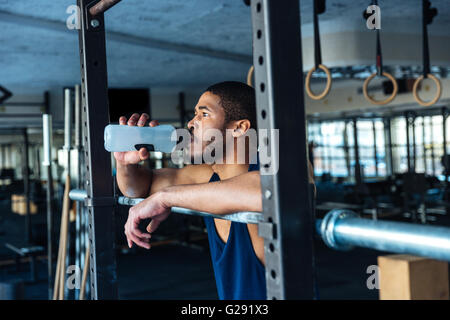 Remise en forme de l'eau potable saine l'homme tout en se reposant dans la salle de sport Banque D'Images