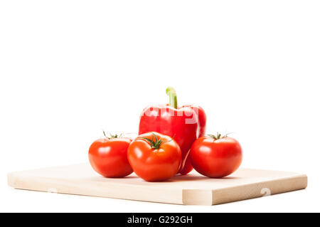 De belles tomates rouges, un gros poivron rouge sur planche de bois isolé sur fond blanc. Banque D'Images