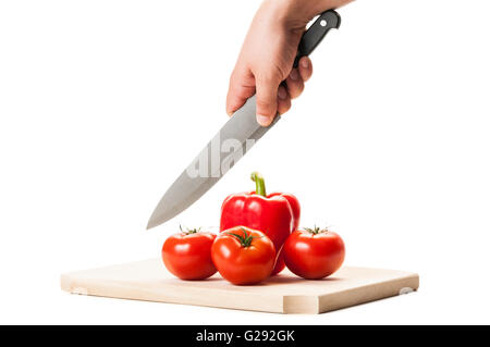 Trois tomates parfait et un poivron rouge prêt à être coupé sur une planche en bois avec un fond blanc Banque D'Images