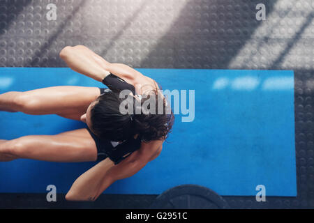 Vue aérienne de femmes travaillant hors de la salle de sport. Muscular young woman doing sit ups sur un tapis d'exercice. Banque D'Images