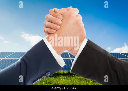 Poignée d'affaires comme d'équipe sur panneau photovoltaïque solarpower arrière-plan. L'accord de partenariat en matière d'énergie renouvelable Banque D'Images