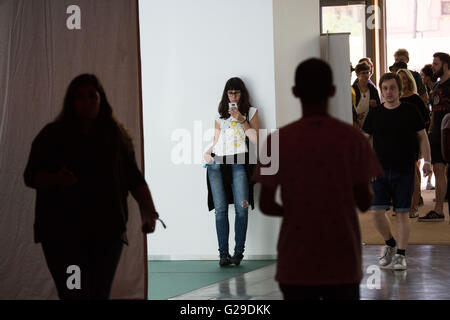 Une femme de poche fait défiler son téléphone portable à l'arrière de l'auditorium principal du Museu del Disseny, Barcelone, le 26 mai 2016. Le premier jour du festival OFFF (alimentons le futur) à Barcelone. Ce festival de design en est maintenant à sa 16e année. Sur la photo : photos générales de la zone de l'auditorium et des personnes assistant au festival. Crédit : Rob Watkins/Alamy Live News Banque D'Images