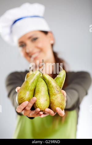 Woman holding a bunch of cook et poires smiling Banque D'Images