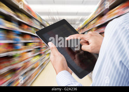 Businessman checking inventaire en supermarché sur écran tactile Tablet. Arrière-plan flou Banque D'Images