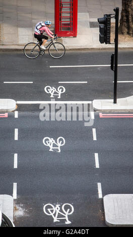 Une vue aérienne d'un cycliste à une voie cyclable passant une boîte de téléphone rouge avec trois signes du cycle sur le remblai à Londres Banque D'Images