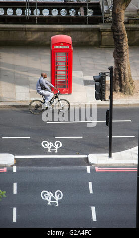 Une vue aérienne d'un cycliste à une voie cyclable passant un téléphone rouge fort withtwo signes cycle sur le remblai à Londres Banque D'Images