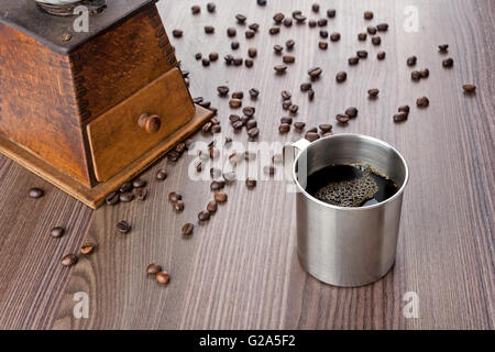 Tasse de café métallique, ancien moulin en bois sur la gauche et les haricots sur la table Banque D'Images