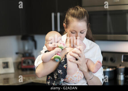 Mère embrassant bébé fille (2-5 mois) pieds Banque D'Images