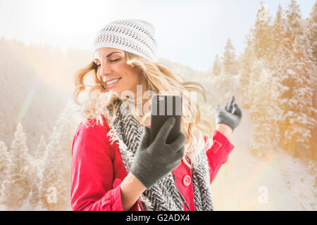 Jeune femme portant des vêtements d'hiver danse avec smart phone in hands Banque D'Images