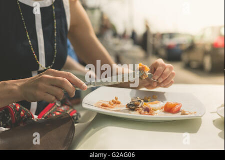 Une jeune femme est d'avoir un petit-déjeuner anglais traditionnel à une table à l'extérieur d'un café sur la rue Banque D'Images