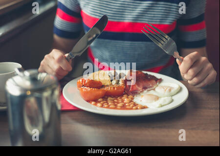 Une jeune femme est d'avoir un petit-déjeuner anglais traditionnel dans un diner Banque D'Images
