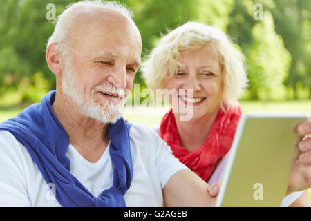 Happy senior couple with tablet PC dans la nature en été Banque D'Images