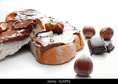 Deux tranches de pain avec la crème au chocolat et noisettes isolés blanc Vue de face. Noisettes et décorer le chocolat. Banque D'Images