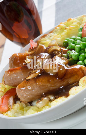 Un classique anglais plat de saucisses et purée. Servi avec des petits pois frais et de la sauce. Banque D'Images