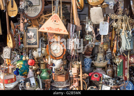 Présentoir de magasin d'occasion Dimotiki Agora Athènes Grèce // ATHÈNES, Grèce — Un magasin général d'occasion près de l'Agora Dimotiki présente une collection diversifiée d'articles d'occasion et neufs, y compris des horloges, de la poterie, de l'art mural, des instruments de musique et des outils. Ce type de boutique éclectique ajoute au caractère du quartier central du marché d'Athènes, offrant un contraste avec les stands de nourriture fraîche de l'Agora Varvakios voisine. Banque D'Images