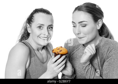 Deux femme vêtue de vêtements fitness s'énerver à propos de manger un muffin Banque D'Images