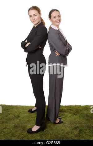 Longueur totale studio shot of successful business couple avec les bras croisés, debout dos à dos sur l'herbe. Isolé sur whit Banque D'Images
