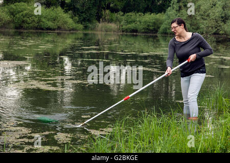 Les biologistes prend un échantillon d'eau dans un étang envahi. Banque D'Images