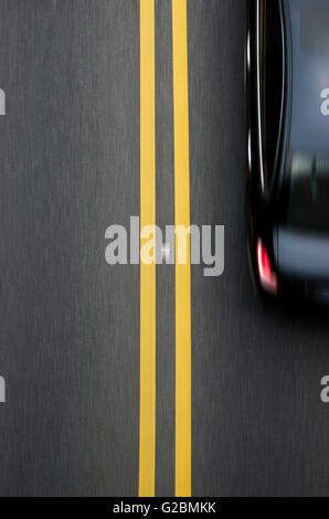 Les lignes jaunes sur le diviseur double revêtement avec une voiture passe Banque D'Images