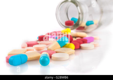 Pilules colorées close-up avec déversés par pot isolé sur fond blanc Banque D'Images
